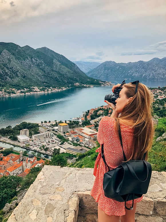 Young woman on vacation taking photos with digital camera